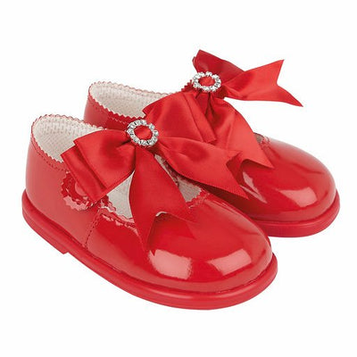 Adorable for little girls taking their first steps, a red pair of first-walker toddler shoes, made from soft patent faux leather. From our Baypods collection, these sweet shoes fasten with a small button strap and have large ribbon bows and diamanté trims. They have a soft rubber sole to provide flexibility and stability.  . Soft patent faux leather uppers Flexible rubber sole Button strap fastening 
