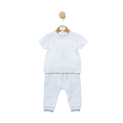 Expertly designed for boys, this blue two piece top and trouser set offers both style and comfort. The round neck short sleeve t-shirt features a subtle grey and white piping detail around the collar, with a button fastening on the reverse and the MB logo on the front. The trousers have an elasticated waistband and string fastening, as well as convenient pockets on each side. Available in sizes from 3 months up to 5 years.
