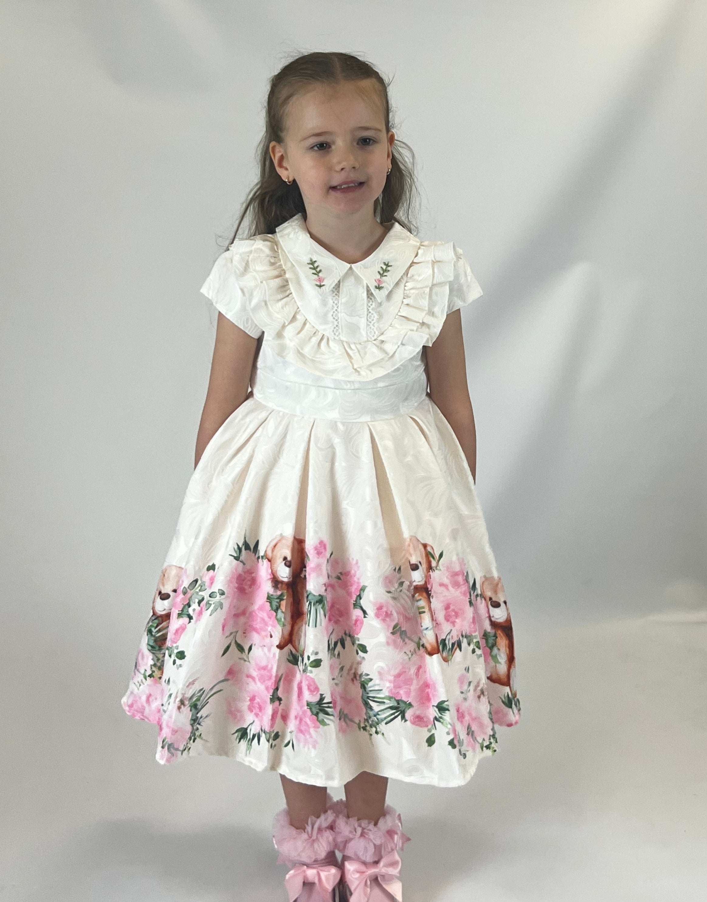 Upgrade your little one's wardrobe with our girls ivory & pink floral teddy bear dress. Made from soft, high-quality fabric, this dress features a charming pink floral design with a sweet teddy bear motif. The collar and front frill add a touch of elegance, making it a perfect addition to our Beau Kid spring summer collection. Available in sizes 6-12 months up to 4-5 years old.