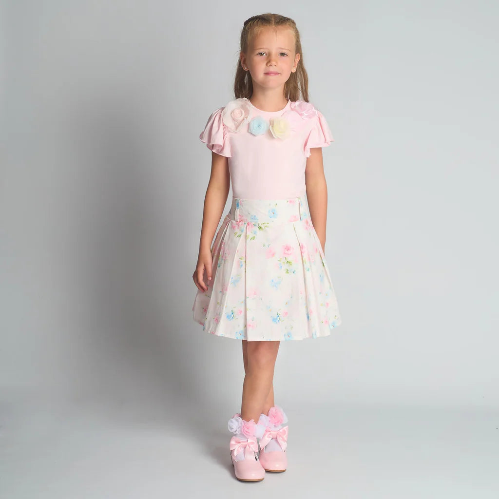 Full-length studio shot of the Beau Kid girls floral 2-piece set featuring a white t-shirt with 3D flower appliqué and a matching pleated floral skirt.