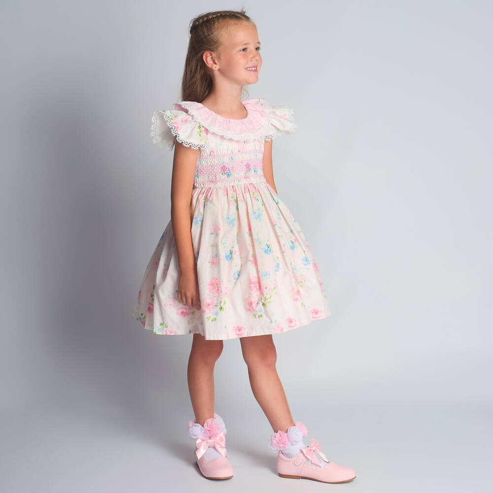 Full studio shot of the Beau Kid girls smart ivory and pink smocked floral dress, a must-have for luxury boutique childrenswear collections.