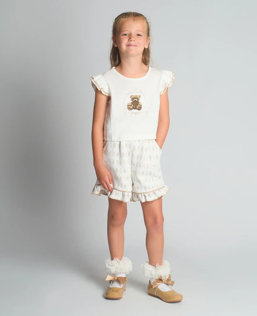 A studio shot of a girl wearing the Beau Kid camel two-piece jersey set featuring a teddy bear graphic top with a ruffled hem and matching shorts.