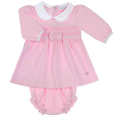 Get your little girl ready for the autumn and winter season with our adorable girls pink smocked dress with pants from childrenswear brand Amore by Kris X Kids. This long sleeve dress features smocked design and a cute bow in the middle, paired with a white collar and button fastening on the reverse. Available in sizes 0-3 month up to 18-24 month, this dress comes with matching pants for a complete and stylish outfit. Perfect for your baby girl, keep her cosy and stylish with this collection.