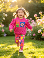 toddler running outdoors in a garden wearing fuchsia pink designer sweatshirt set