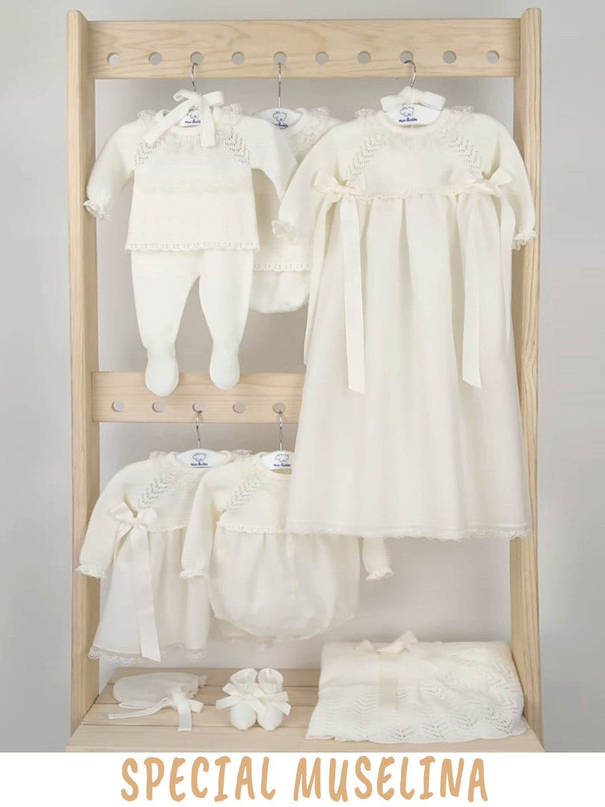Wooden rack with white baby clothing and muselina on a gray background, labeled 'Special Muselina'.
