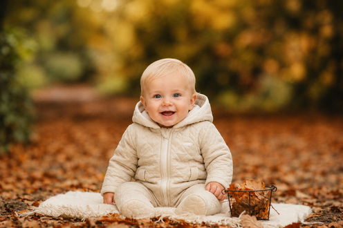 amore baby boys beige quilted pram suit model sitting in autumn leaves luxury infant fashion