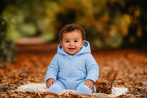 amore baby boys blue quilted pram suit model sitting in autumn leaves luxury infant fashion