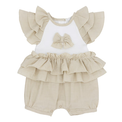 This expertly crafted girls beige &amp; white short sleeve frilly romper by Blues Baby is ideal for your little one. The frilly adornments on the sleeves and waistband, paired with an adorable bow on the front, bring a delightful element to the romper. Offered in sizes 3-9 months.