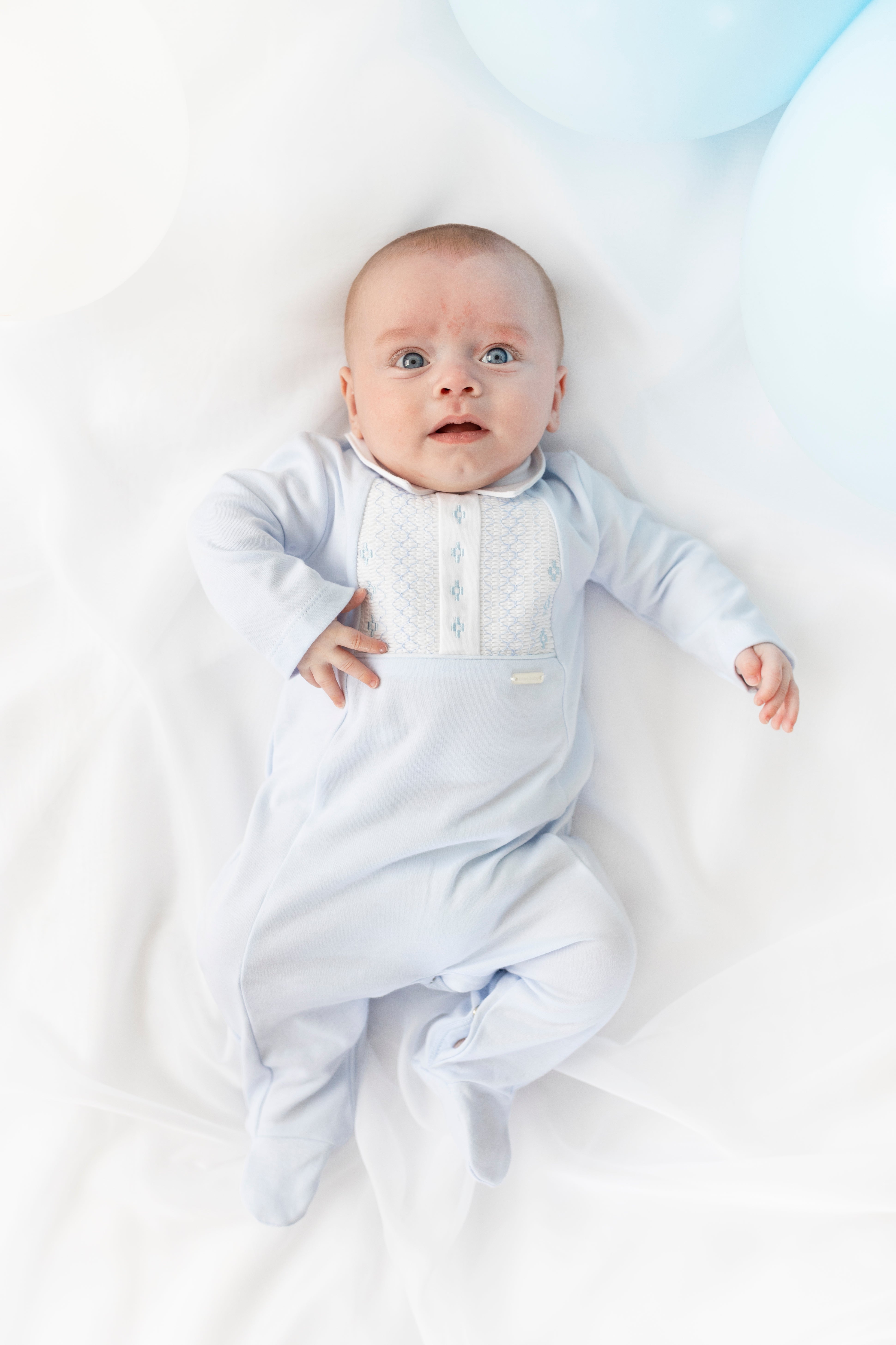 Close up of Blues Baby Cannes sleepsuit showing intricate white smocked chest detail and smart pointed collar