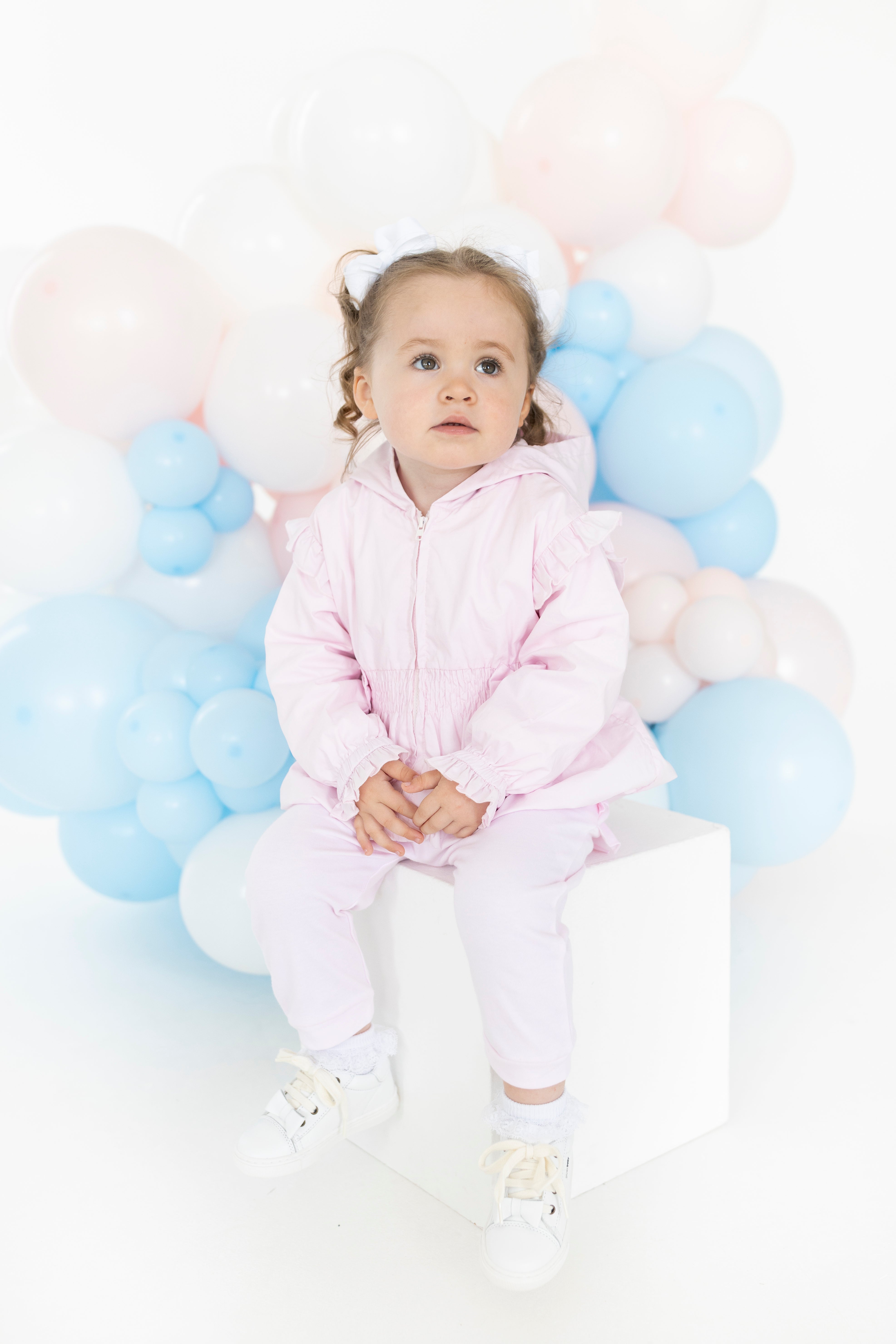 Detail of Blues Baby La Rochelle pink jacket showing ruffle shoulders smocked waist and satin bow accents