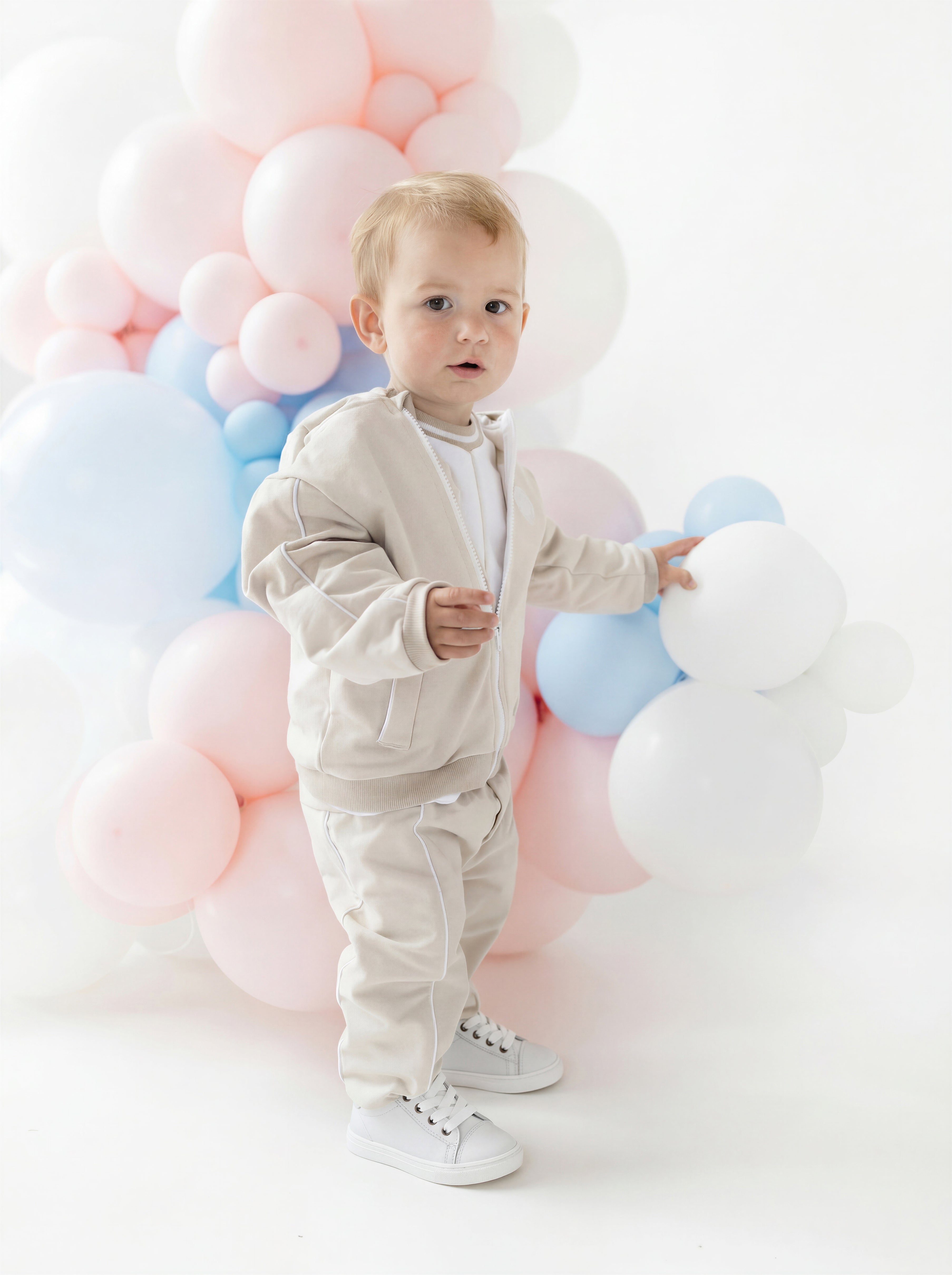 blues baby boys beige hamel zip hoodie top and joggers model standing by balloons boutique childrenswear luxury loungewear