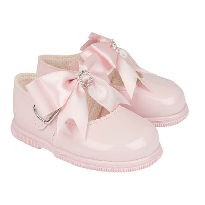 Adorable for little girls taking their first steps, a pink pair of first-walker toddler shoes, made from soft patent faux leather. From our Baypods collection, these sweet shoes fasten with a small button strap and have large ribbon bows and diamanté trims. They have a soft rubber sole to provide flexibility and stability.  Soft patent faux leather uppers Flexible rubber sole Button strap fastening 