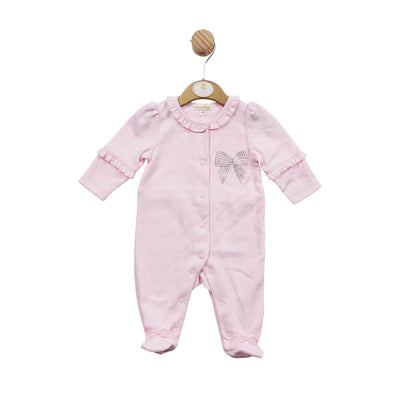 Mintini Baby branded girls pink all in one sleepsuit finished with a sparkly diamanté bow detail to the front and reverse. There is frill detail around the sleeves and collar, with push button fastenings going down the front. Available in sizes 1 month, 3 month and 6 month.