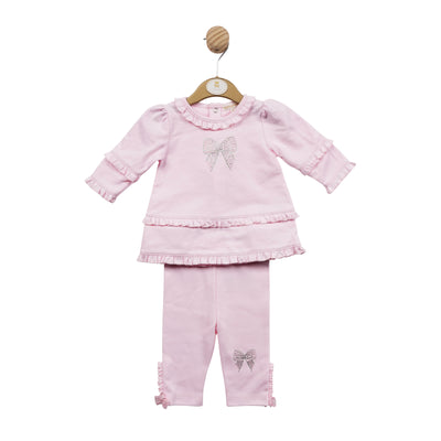 Mintini Baby branded girls tunic and legging set finished in a soft pink colour. This set consists of a long sleeve top with a round neck collar, the collar and sleeves have a small frill detail around them and in the middle of the top there is a diamanté bow design. The leggings have small bows to the ankles and a diamanté bow design on one leg. Available in sizes 3 month up to 24 month.