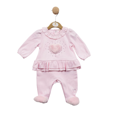 Mintini Baby branded baby girls all in one sleeper finished in a pastel baby pink colour. This sleepsuit has a fluffy fur heart embellishment to the front with diamanté detail going around it, frill detail around the collar as well as around the waistband. Push button fastening on the reverse. Available in sizes 1 month, 3 month & 6 month.