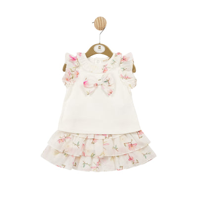 Elevate your little girl's wardrobe with this stunning two piece ivory floral top & skirt set by Mintini Baby. The ivory color and delicate floral detail add a touch of elegance to any occasion. Beautiful floral detail around the shoulders with a large floral bow in the middle of the top, and floral printed skirt to match. Available in sizes 3 months to 5 years old, making it perfect if you want to match little sister with her big sister to create the perfect coordinated look.