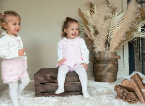 Introduce your little girl to style with this baby girls pink &amp; ivory bow and ruffle romper from childrenswear clothing brand Mintini Baby. This adorable romper features a long sleeve ivory shirt with a frill collar and a pink romper adorned with a charming bow and ruffle details on the sides. With button fastening on the reverse, this romper is as functional as it is stylish. Available in sizes 3 months up to 24 months, this romper is the perfect addition to any little fashionista's wardrobe.