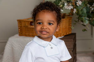 Child wearing a white shirt with a basket and plants in the background