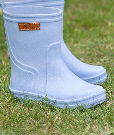 Light blue rain boots with a brand label on grass