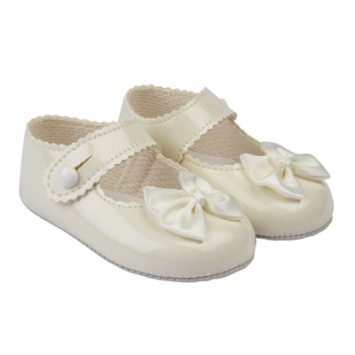 These gorgeous ivory pre-walker baby girl shoes, from our Baypods collection, are beautifully made in soft faux patent leather and have pretty satin bows on the toes. Easy to put on, they secure with a button fastening strap. They have a lightly cushioned insole and their flexible soles are just right for developing feet.   Faux patent leather Lightly cushioned insole  Flexible soles Button fastening strap