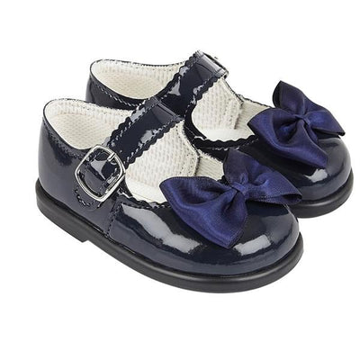 Little girls navy, first walker toddler shoes, from our Baypods collection made from faux patent leather with a pretty satin bow on the front. Traditional in style, they have a classic "Mary Jane" shape and buckle fastening strap. Made in England, they have a rubber sole that is soft and flexible, ideal for growing feet. . First walker  Faux patent leather upper Buckle fastening Flexible rubber sole  Made in England